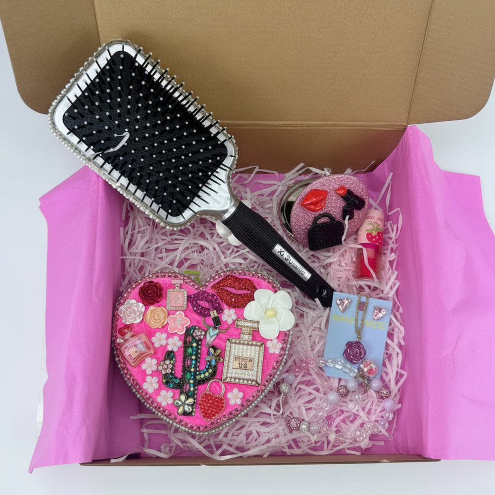 decoden hair brush decorated with rhinestones and charms next to pink heart jewelry box