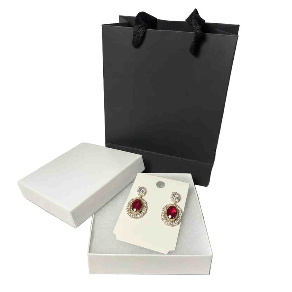 elegant gold-tone earrings with ruby red gemstones, gift box and black paper bag