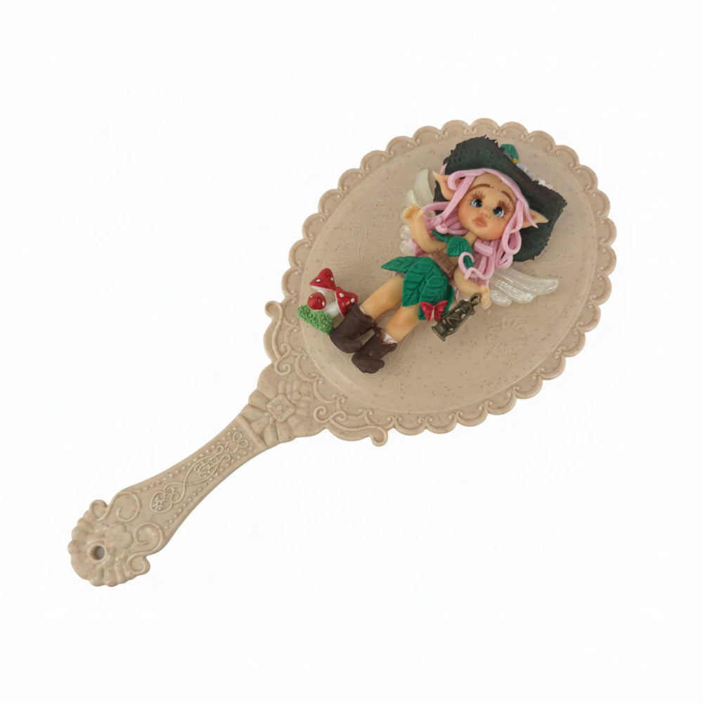 enchanted goblin porcelain flatback embellishment attached to a handheld vanity mirror