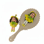 fairy flex porcelain doll with yellow outfit and green flowers next to a decorative hand mirror 