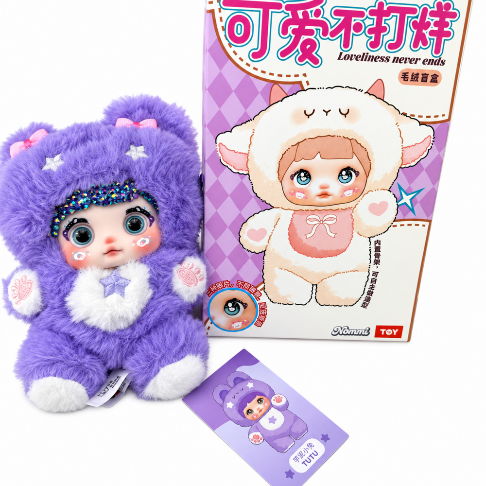 front view of purple nommi plush featuring sparkling forehead crystals, embroidered stars, pink paw details, box, and card.