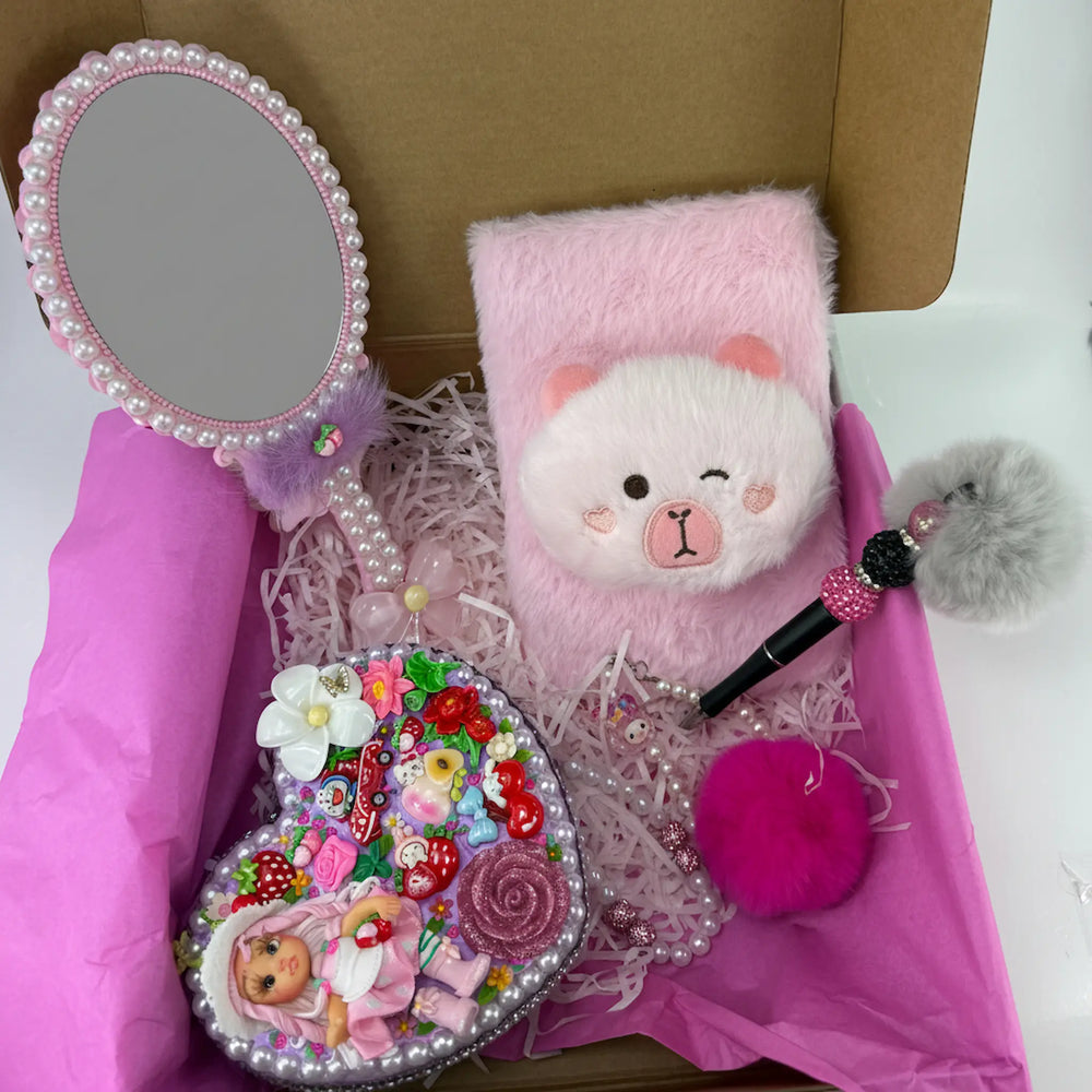 pink decoden hand mirror next to a soft pink plush journal notebook with a cute kawaii bear face